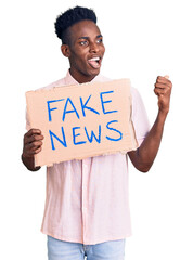 Young african american man holding fake news banner pointing thumb up to the side smiling happy...