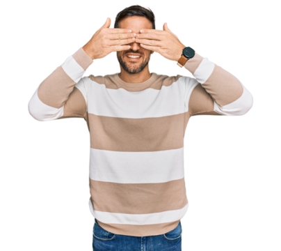 Handsome man with beard wearing casual clothes and glasses covering eyes with hands smiling cheerful and funny. blind concept.