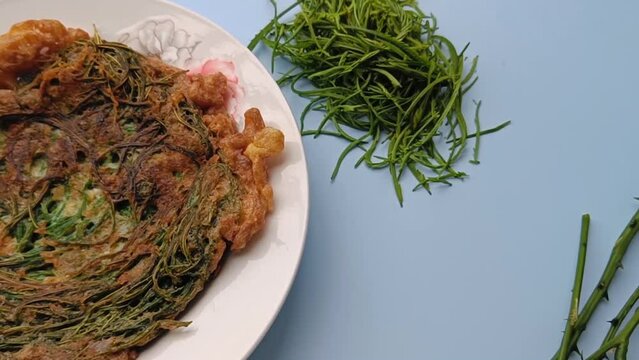 Thai call Kai Jeow Cha Om or omelette with acacia leaves on blue background