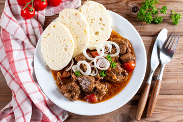 Beef goulash and dumplings (knedliky) on table from Czech Republic