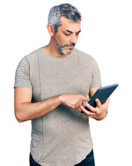 Middle age hispanic with grey hair using touchpad device relaxed with serious expression on face....