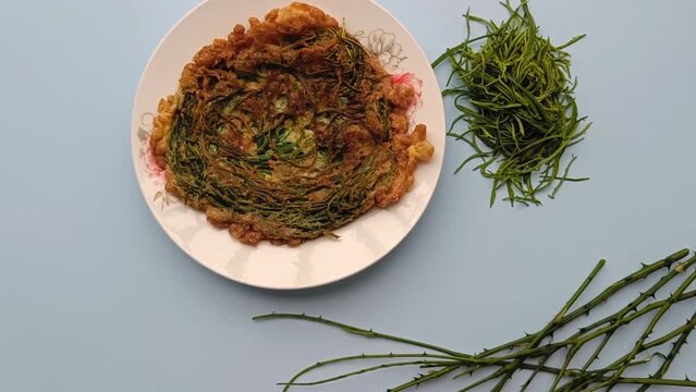 Thai call Kai Jeow Cha Om or omelette with acacia leaves on blue background