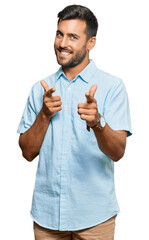 Handsome hispanic man wearing casual clothes pointing fingers to camera with happy and funny face....