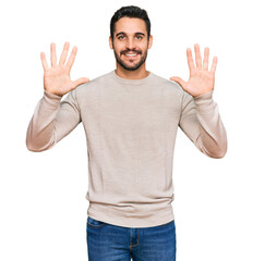 Young hispanic man wearing casual clothes showing and pointing up with fingers number ten while smiling confident and happy.