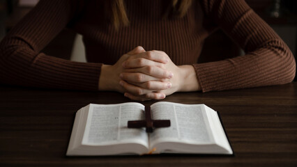 Woman sitting and studying the scriptures.The  wooden cross in the hands. Christian education concepts The Holy Scriptures open and pray to God..