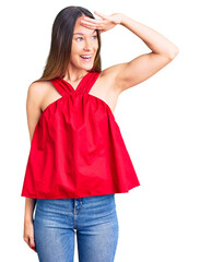 Fototapeta premium Beautiful brunette young woman wearing casual clothes very happy and smiling looking far away with hand over head. searching concept.