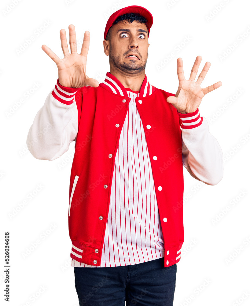 Sticker young hispanic man wearing baseball uniform afraid and terrified with fear expression stop gesture w