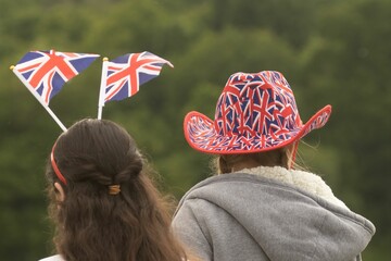 Rear view of two young ladies celebrating being British with Union Jack flags - obrazy, fototapety, plakaty