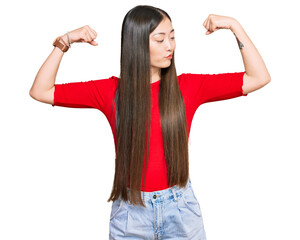 Young chinese woman wearing casual clothes showing arms muscles smiling proud. fitness concept.