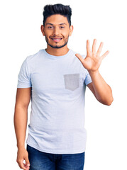 Handsome latin american young man wearing casual clothes showing and pointing up with fingers number five while smiling confident and happy.