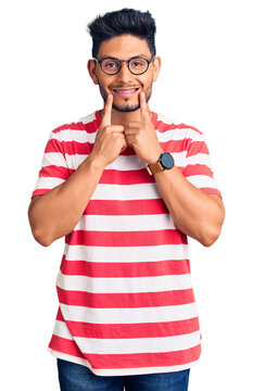 Handsome latin american young man wearing casual clothes and glasses smiling with open mouth, fingers pointing and forcing cheerful smile