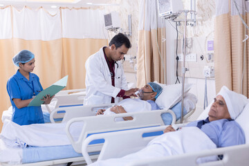 Obraz premium Nurse with male doctor examining of patient lying on icu bed at hospital 