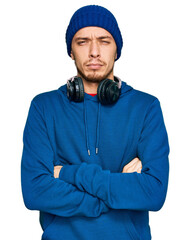 Hispanic young man wearing sweatshirt and wool hat skeptic and nervous, disapproving expression on face with crossed arms. negative person.