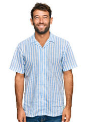 Handsome young man with beard wearing casual fresh shirt with a happy and cool smile on face. lucky person.