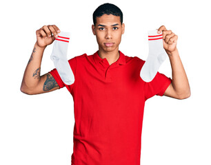 Young hispanic man holding socks depressed and worry for distress, crying angry and afraid. sad...