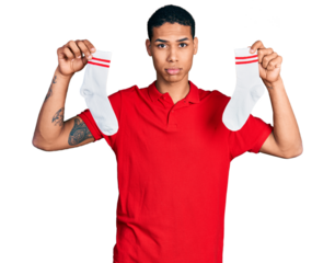 Young hispanic man holding socks depressed and worry for distress, crying angry and afraid. sad expression.