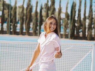 Hispanic female smiling and posing with a tennis racket