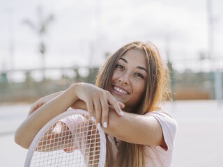 Portrait of a Hispanic female smiling and posing with a tennis racket