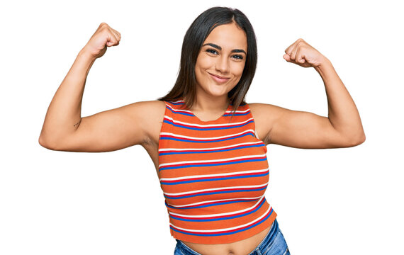 Young brunette woman wearing casual clothes showing arms muscles smiling proud. fitness concept.