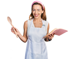Young caucasian woman wearing professional baker apron reading cooking recipe book winking looking at the camera with sexy expression, cheerful and happy face.