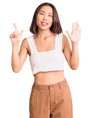 Young beautiful chinese girl wearing casual clothes showing and pointing up with fingers number seven while smiling confident and happy.