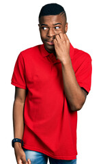 Young african american man wearing casual red t shirt looking stressed and nervous with hands on mouth biting nails. anxiety problem.