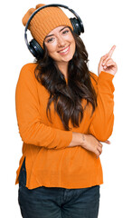 Beautiful brunette young woman listening to music using headphones with a big smile on face,...