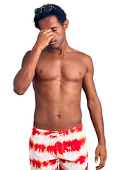 Fototapeta premium African handsome man wearing swimsuit and sunglasses tired rubbing nose and eyes feeling fatigue and headache. stress and frustration concept.
