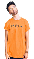 Young hispanic man wearing t shirt with happiness word message looking sleepy and tired, exhausted for fatigue and hangover, lazy eyes in the morning.