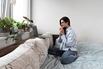 Obraz premium Young freelancer business woman talking on video call from home on her laptop computer while she is sick. Ill female have web conference about important business solutions with her colleagues.