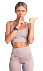 Beautiful caucasian woman wearing sportswear asking to be quiet with finger on lips pointing with hand to the side. silence and secret concept.