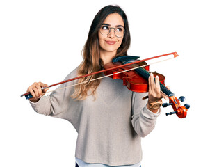 Beautiful hispanic woman playing violin smiling looking to the side and staring away thinking.