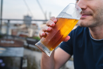 A young man is drinking beer on rooftop during the day