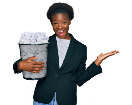 Young african american girl holding paper bin full of crumpled papers celebrating victory with happy smile and winner expression with raised hands