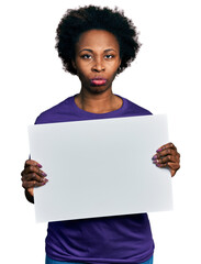 African american woman with afro hair holding blank empty banner skeptic and nervous, frowning upset because of problem. negative person.