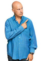 Middle age bald man wearing casual clothes pointing with hand finger to the side showing advertisement, serious and calm face