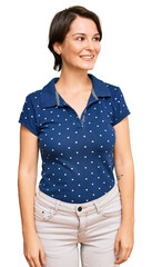 Fototapeta premium Young brunette woman with short hair wearing casual clothes looking away to side with smile on face, natural expression. laughing confident.
