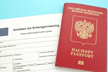 Schengen visa application form in Swedish language and passport on blue background. Prohibition and suspension of visas for Russian tourists to travel to European Union and the Baltic States concept