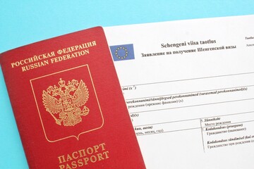 Schengen visa application form in Russian and Estonian language and passport on blue background. Prohibition and suspension of visas for Russian tourists to travel to Europe Union and Baltic States