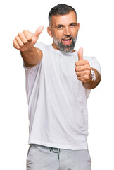 Middle age handsome man wearing casual white tshirt approving doing positive gesture with hand, thumbs up smiling and happy for success. winner gesture.