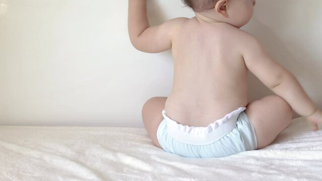 Cute Little Boy Toddler Get Up And Fall On Butt Walking Along Bed Holding From Edge.first Steps Baby Fail To Walk By Itself.big Brother Hand Playing With Infant.child Wearing Washable Reusable Pants