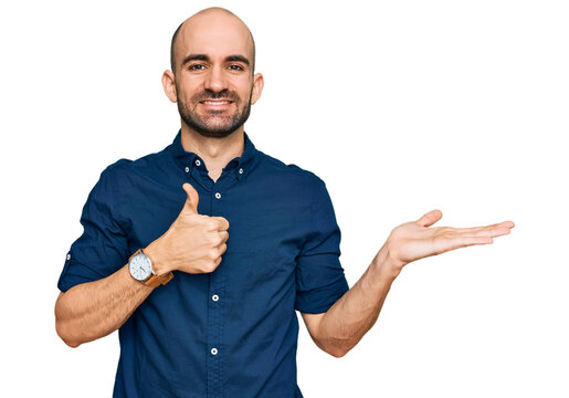Young hispanic man wearing casual clothes showing palm hand and doing ok gesture with thumbs up, smiling happy and cheerful