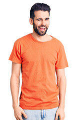 Obraz premium Young handsome man with beard wearing casual t-shirt winking looking at the camera with sexy expression, cheerful and happy face.