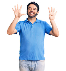 Young hispanic man wearing casual clothes showing and pointing up with fingers number nine while smiling confident and happy.