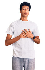 Young african american man wearing casual clothes smiling with hands on chest with closed eyes and grateful gesture on face. health concept.