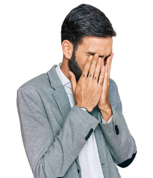 Young hispanic man wearing business clothes with sad expression covering face with hands while crying. depression concept.