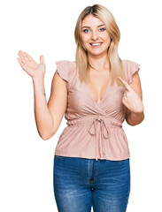 Young caucasian woman wearing casual clothes amazed and smiling to the camera while presenting with hand and pointing with finger.