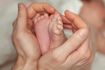 Newborn cute feet in young father hands. Lovely, emotional moment closeup