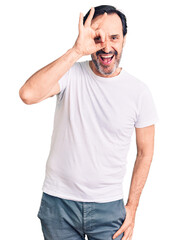 Middle age handsome man wearing casual t-shirt doing ok gesture with hand smiling, eye looking through fingers with happy face.