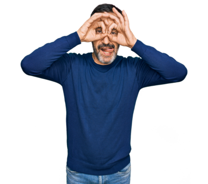 Middle age hispanic man wearing casual clothes doing ok gesture like binoculars sticking tongue out, eyes looking through fingers. crazy expression.